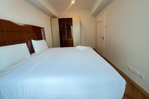 Une chambre d’hôtel avec un grand lit, une armoire et une porte donnant sur une salle de bain.