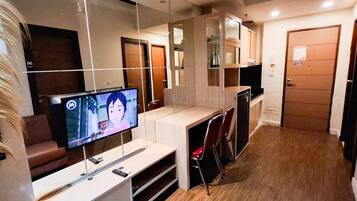 Una sala de estar moderna con un televisor de pantalla plana, piso de madera y un muro divisorio de vidrio.