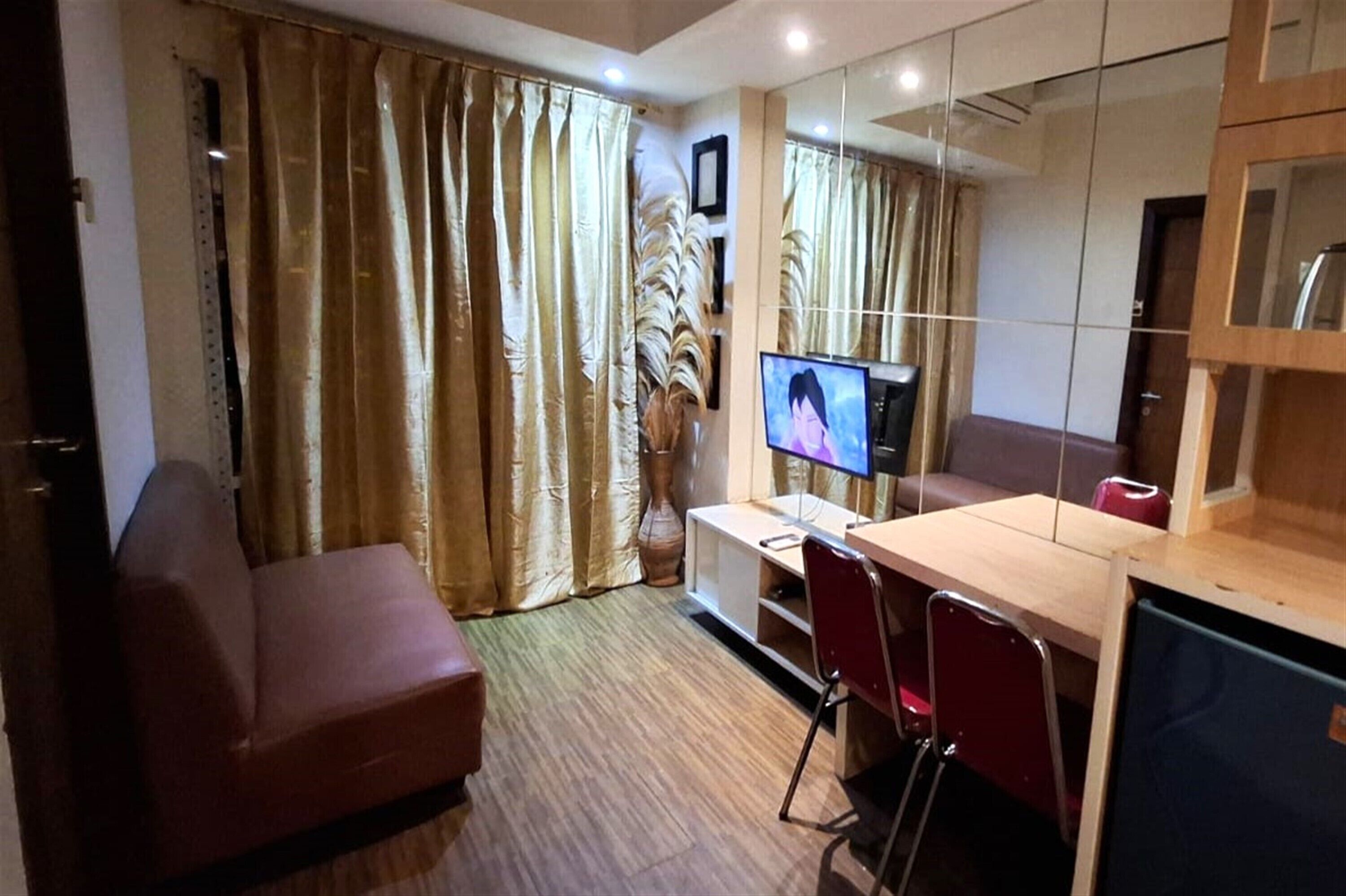 A compact living space with a sofa, a desk with a computer, and a television.