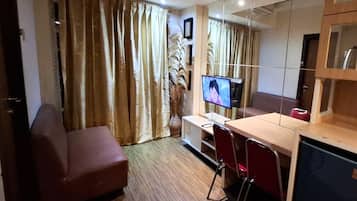 A compact living space with a sofa, a desk with a computer, and a television.