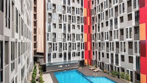 A modern building with a central swimming pool surrounded by balconies. - Nice Look Studio Apartment at The Alton (Semarang)