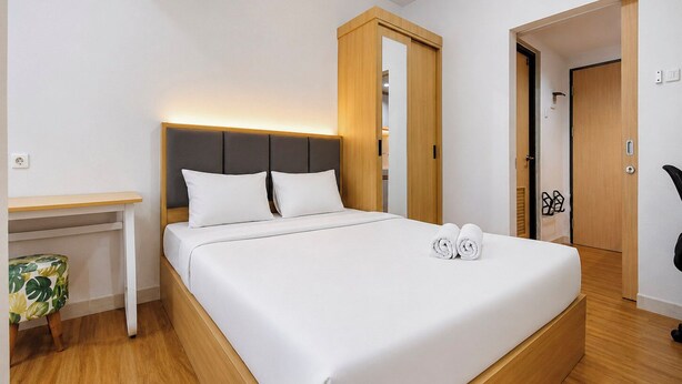 A hotel room with a bed, a desk, and a wardrobe. - Nice Look Studio Apartment at The Alton (Semarang)