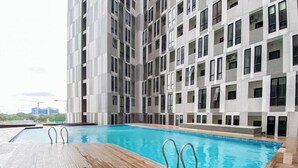 A modern building with a swimming pool and a wooden deck. - Nice Look Studio Apartment at The Alton (Semarang)