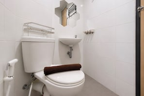 A modern bathroom with a toilet, sink, and towel rack. - Nice Look Studio Apartment at The Alton (Semarang)