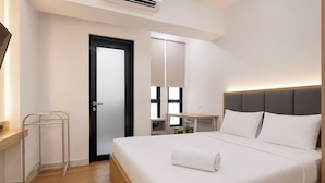 A hotel room with a bed, bedside table, and a mirror. - Nice Look Studio Apartment at The Alton (Semarang)