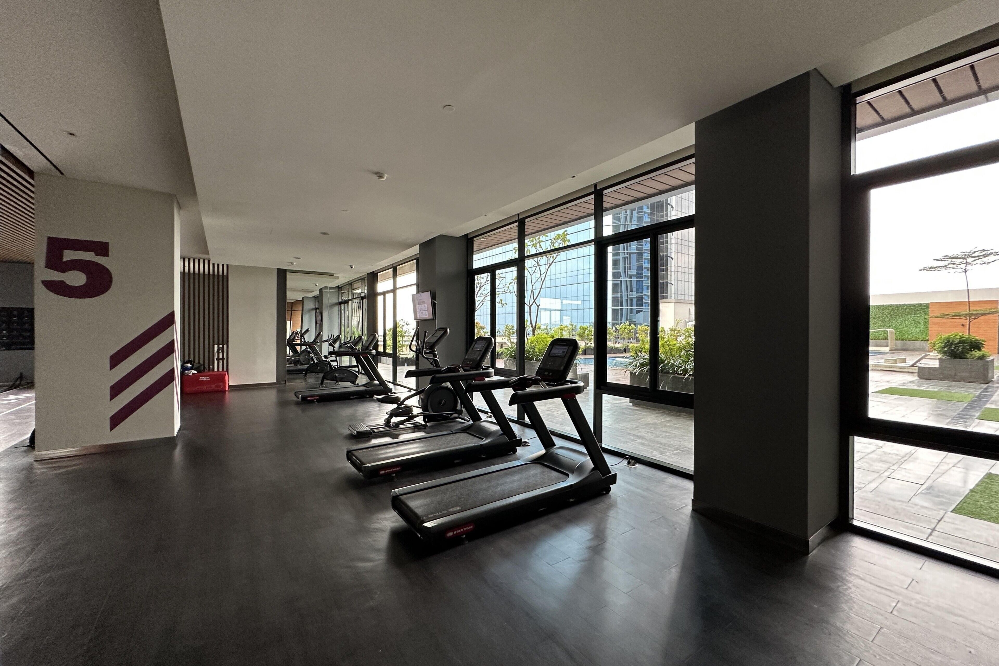Un gimnasio con cintas de correr, bicicletas estáticas y un amplio ventanal con vistas al exterior.