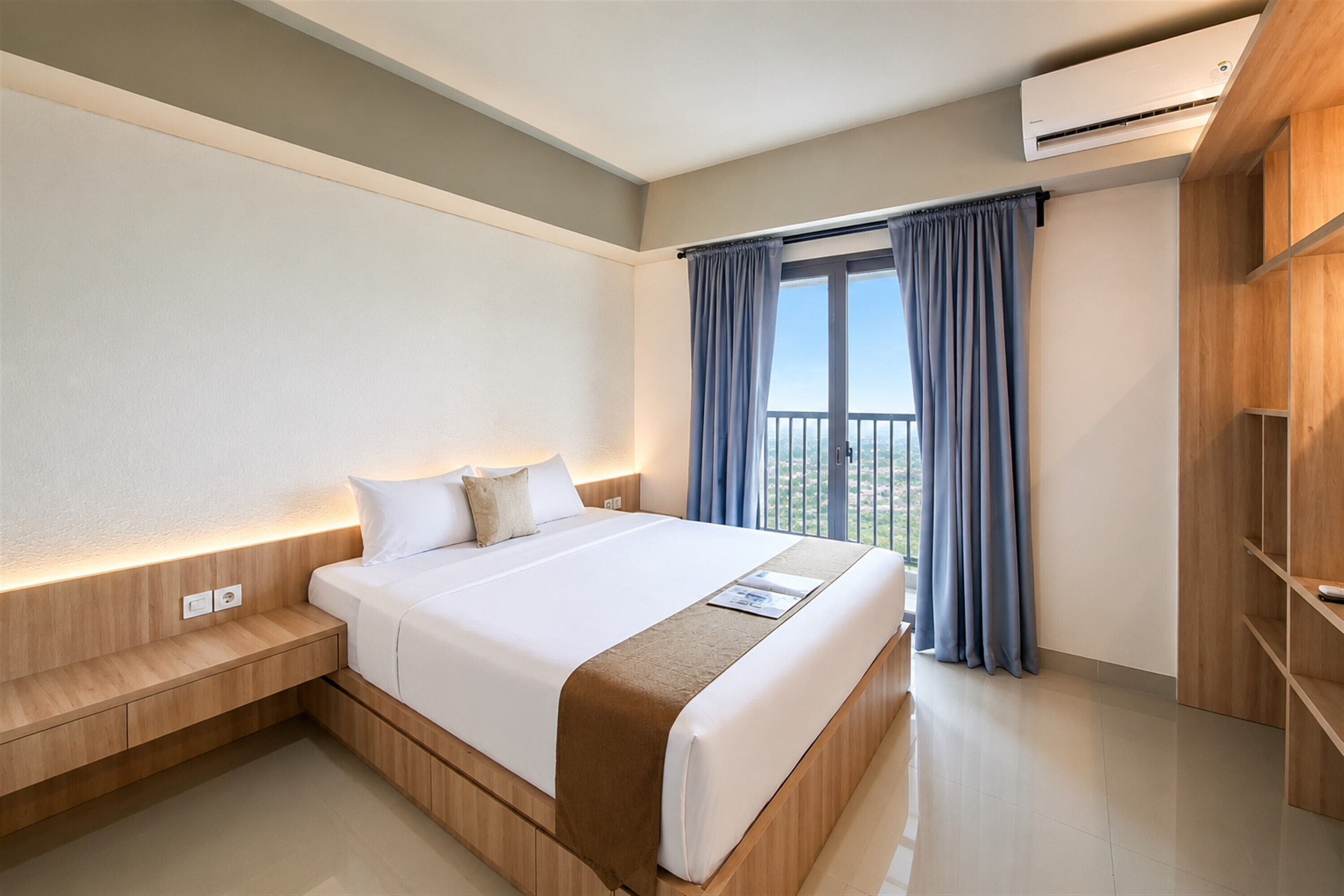 A hotel room with a large bed, a nightstand, a wooden wardrobe, and a window with curtains.