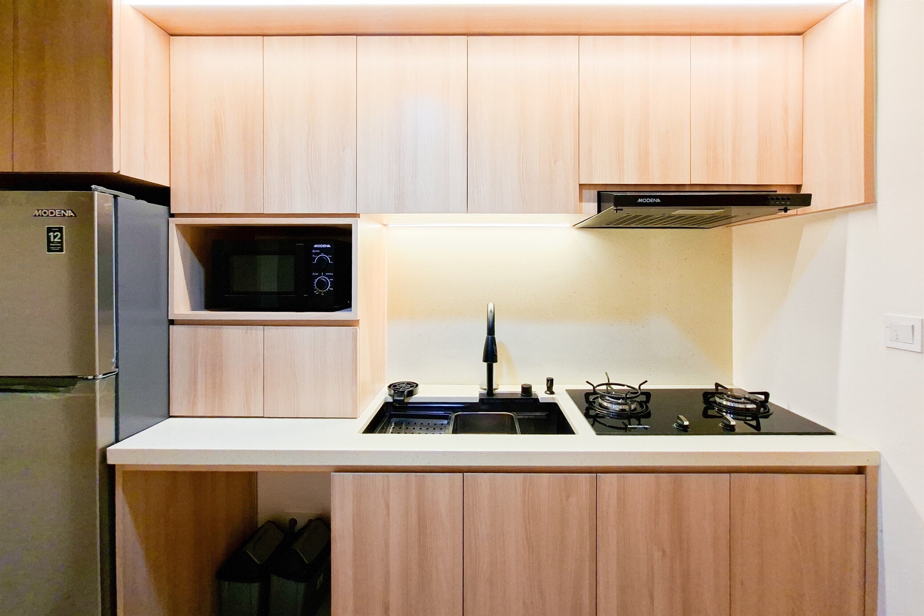 A compact kitchen with a refrigerator, microwave, stove, and sink.
