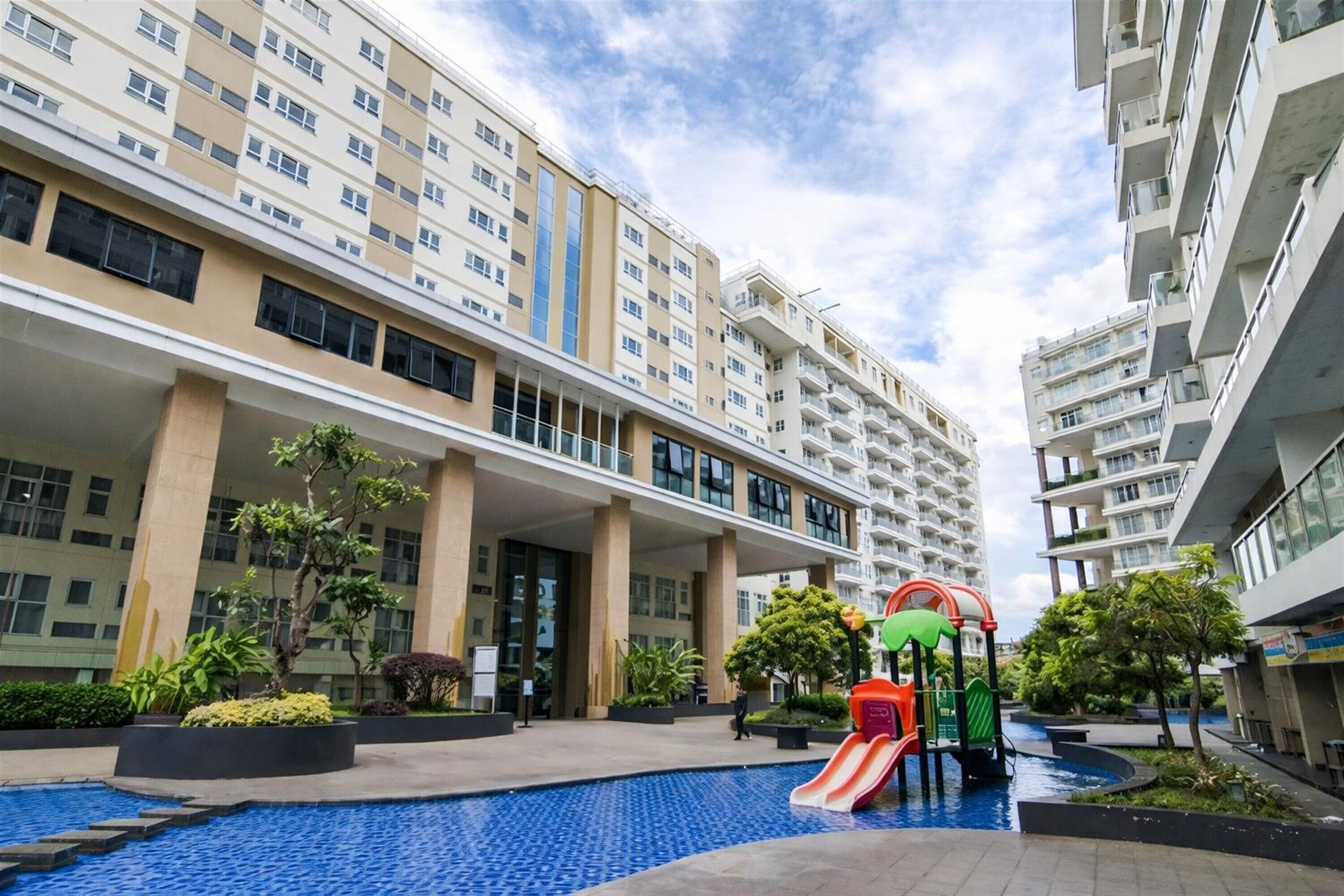 Un edificio residencial con piscina y zona de juegos para niños.