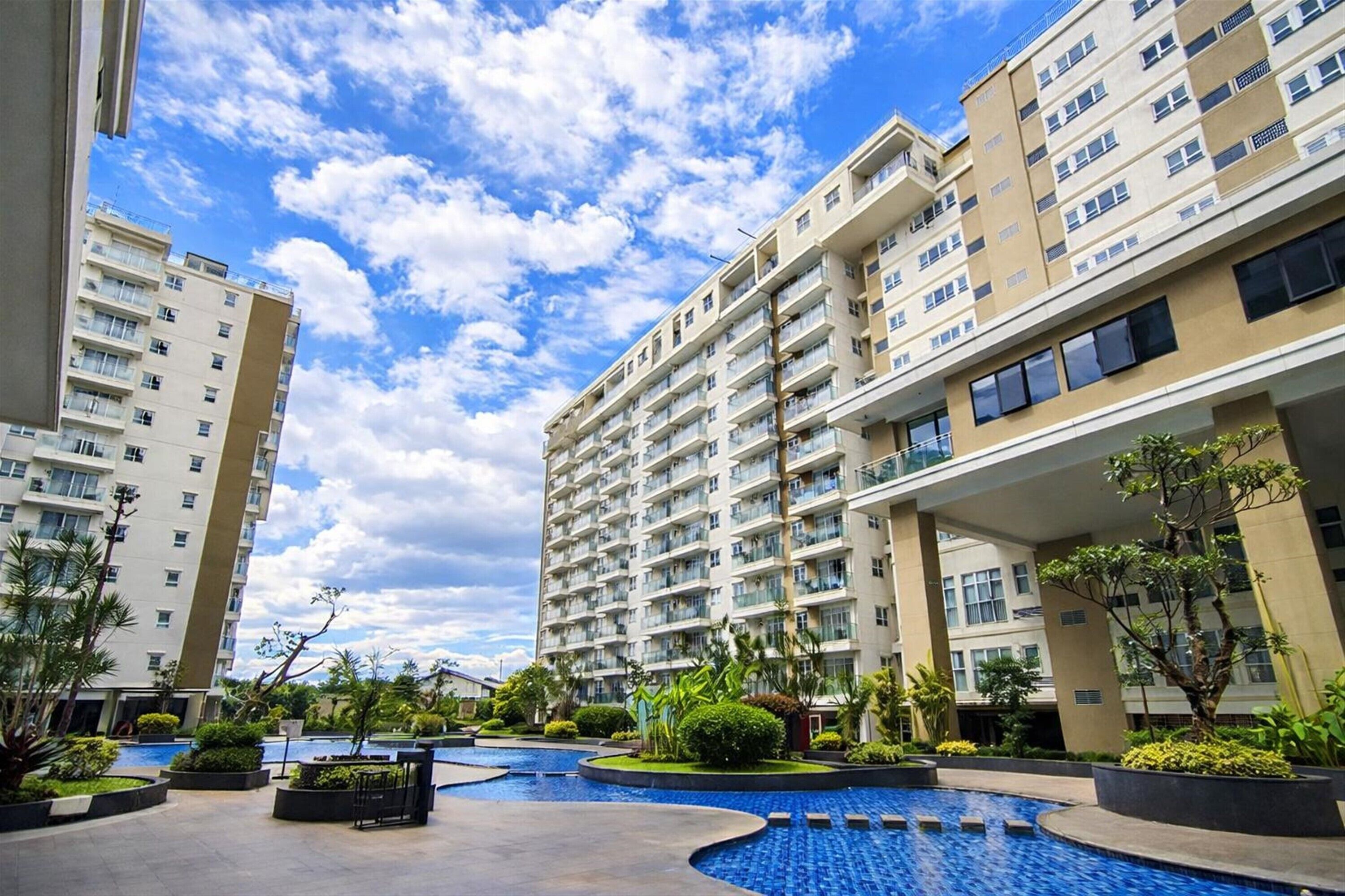 Un edificio residencial con varios balcones, piscina rodeada de vegetación.
