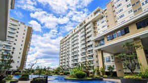A residential building with multiple balconies, a swimming pool, and surrounding greenery. - Comfortable 2Br At Gateway Pasteur Apartment (Bandung)