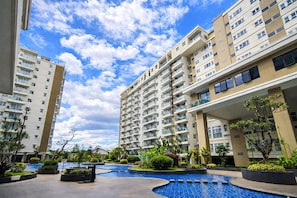 A residential building with multiple balconies, a swimming pool, and surrounding greenery. - Comfortable 2Br At Gateway Pasteur Apartment (Bandung)