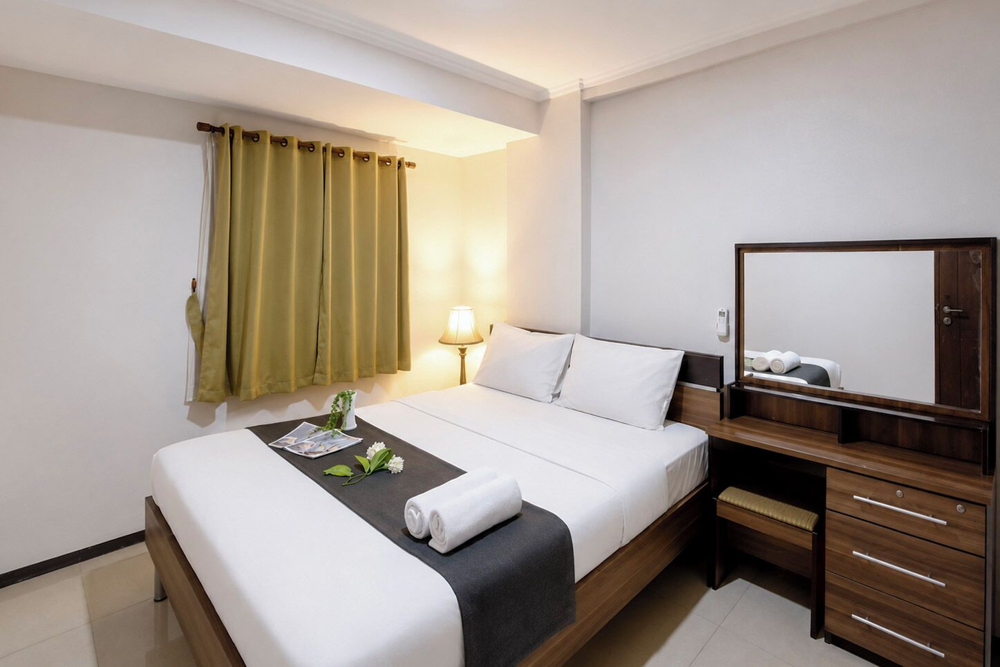 Una habitación de hotel con cama, mesita de noche, lámpara y espejo.