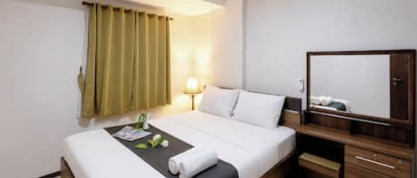 A hotel room with a bed, bedside table, lamp, and a mirror.