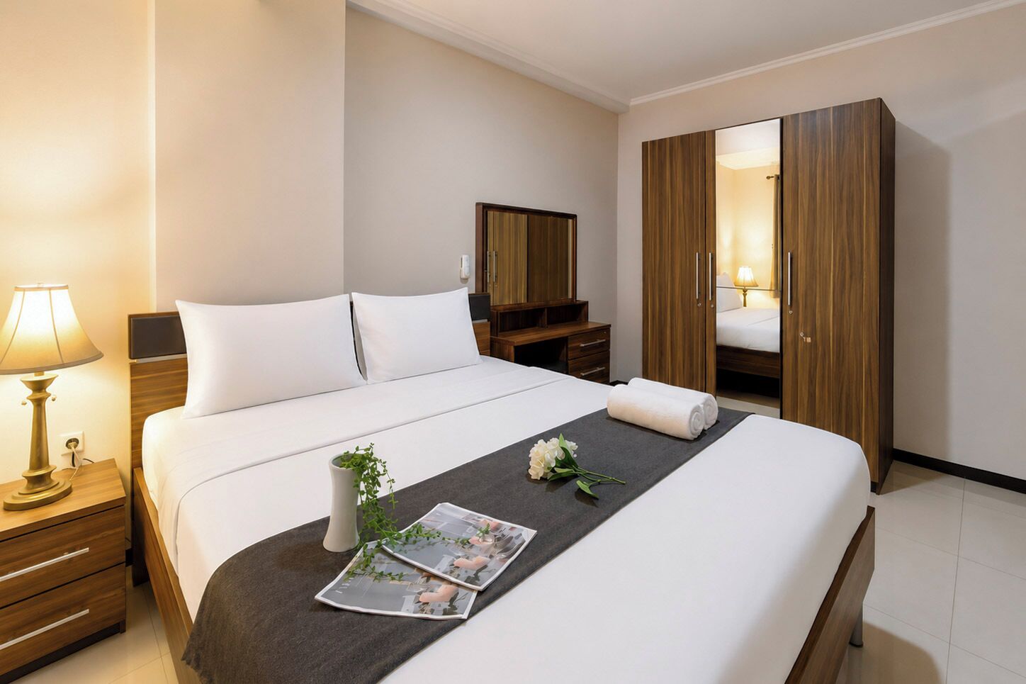 Quarto de hotel com cama, mesas de cabeceira, guarda-roupa e espelho.