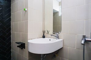 Ein Badezimmer mit einem weißen Waschbecken, einem Spiegel und einem schwarzen Handtuchhalter.