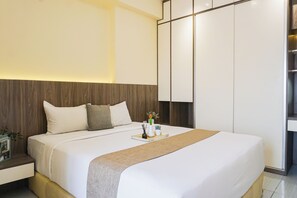 Ein modernes Schlafzimmer mit einem großen Bett, einem hölzernen Kopfteil und einem Nachttisch mit Blumen.