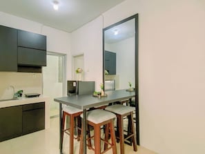 Cozinha moderna com área de refeições, incluindo geladeira, pia e banquetas de bar.