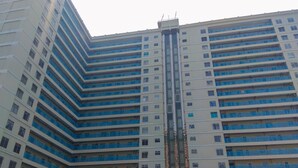A multi-story building with a central vertical feature, possibly a lift shaft, surrounded by balconies. - Airy And Modern 2Br At Apartment Teluk Intan (Jakarta)