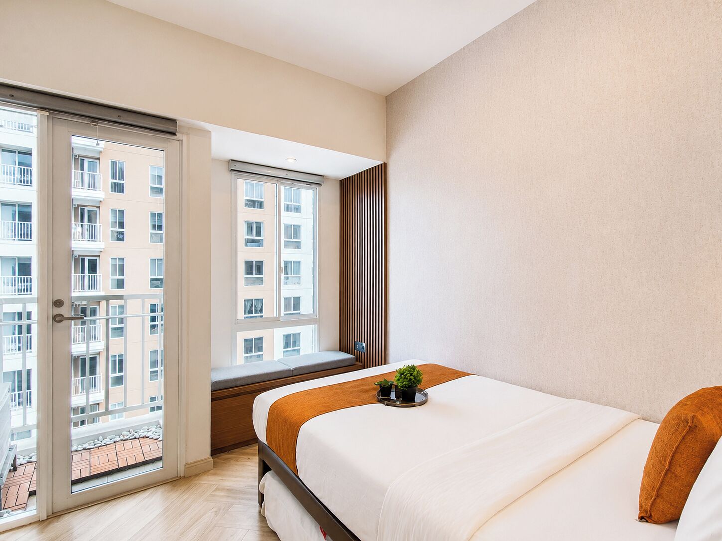 Quarto com cama, janela e vista de um edifício.
