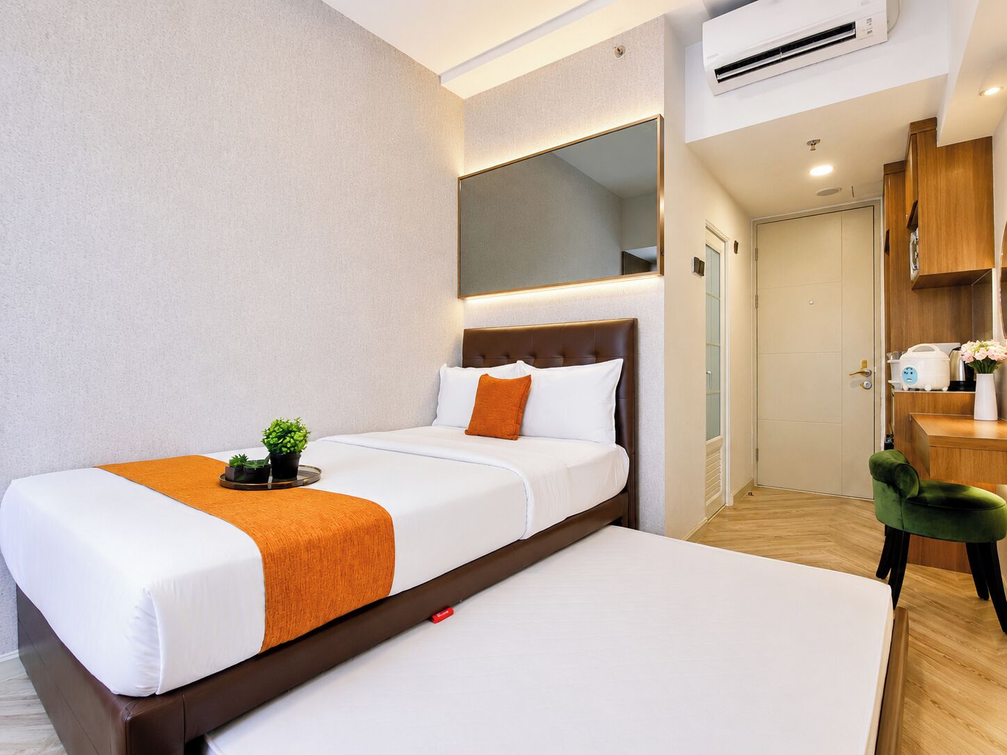 A hotel room with a bed, bedside table, and a small desk area with a chair.