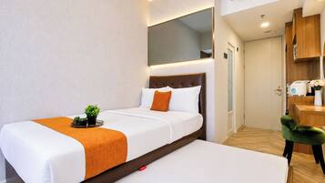 A hotel room with a bed, bedside table, and a small desk area with a chair.