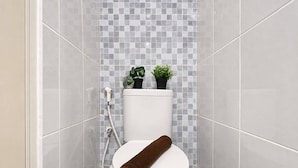 A bathroom with a toilet, a shower, and a tiled wall. - Modern Well Located Studio Room At Apartment Tokyo Riverside Pik 2 (Jakarta)