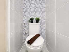 A bathroom with a toilet, a shower, and a tiled wall.