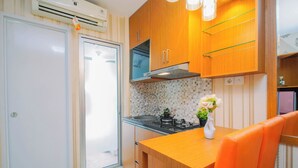 Una cocina compacta con estufa integrada, armarios de madera y un pequeño comedor con mesa y sillas.
