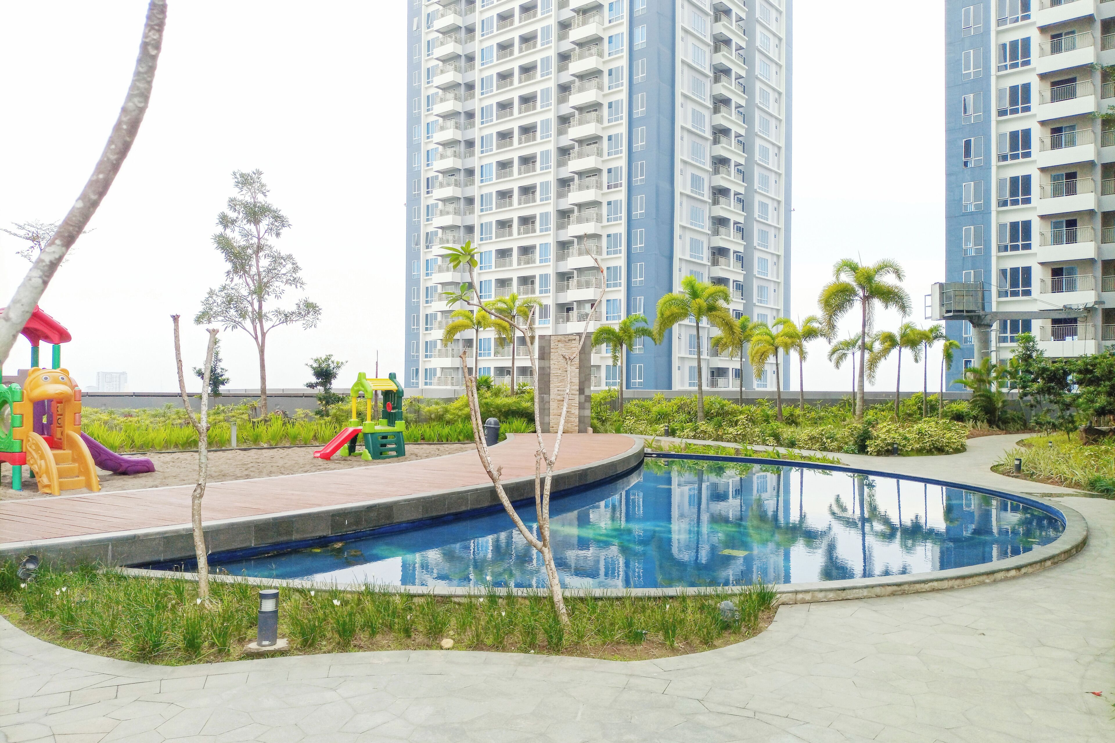 Zona residencial con piscina, parque infantil y edificios altos al fondo.