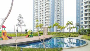 Ett bostadsområde med en swimmingpool, en lekplats och höga byggnader i bakgrunden.