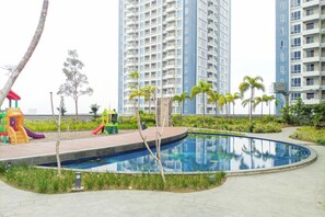 Ein Wohngebiet mit Schwimmbad, Spielplatz und Hochhäusern im Hintergrund.