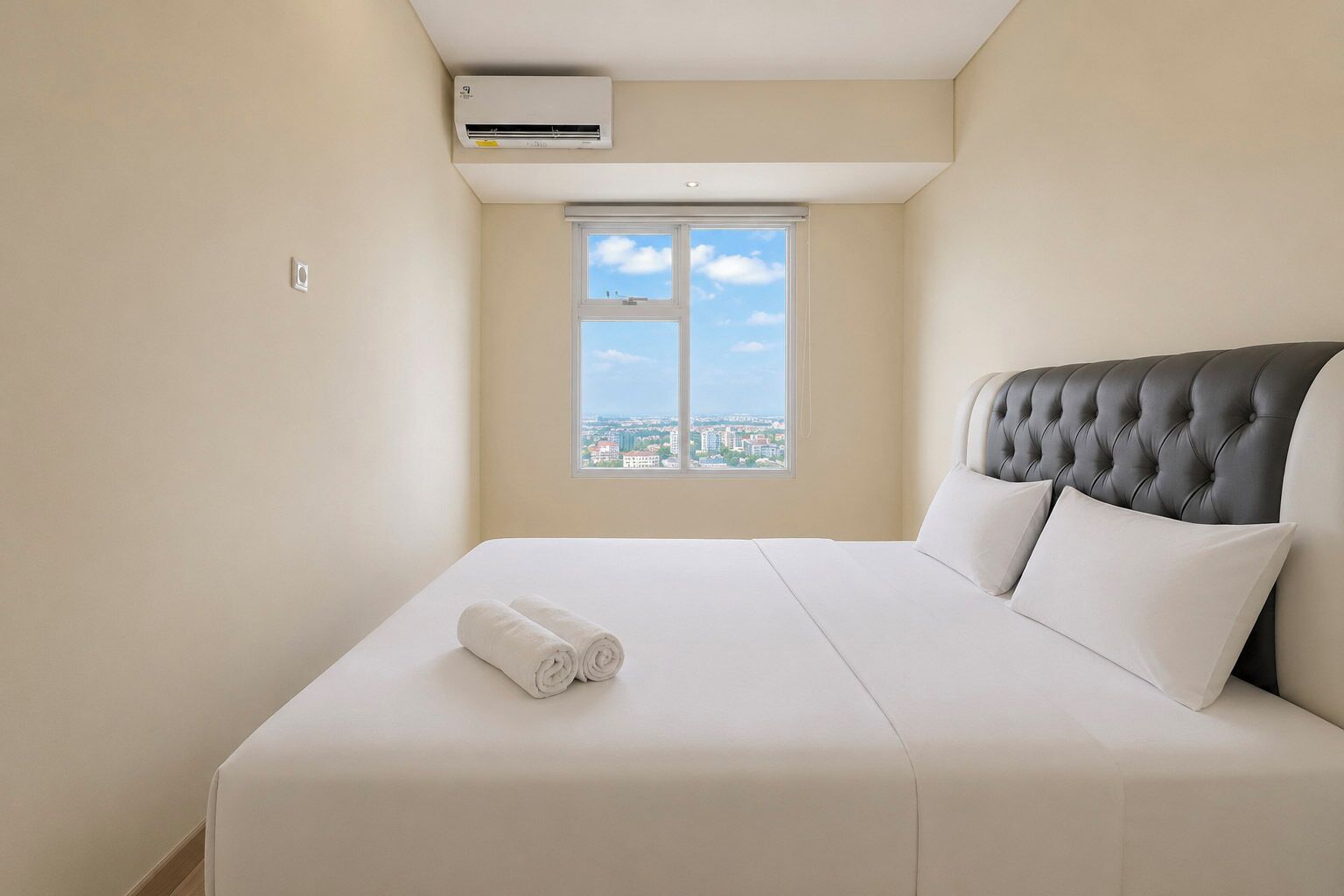 Une chambre d’hôtel avec un lit, une fenêtre donnant sur la ville et un appareil de climatisation.
