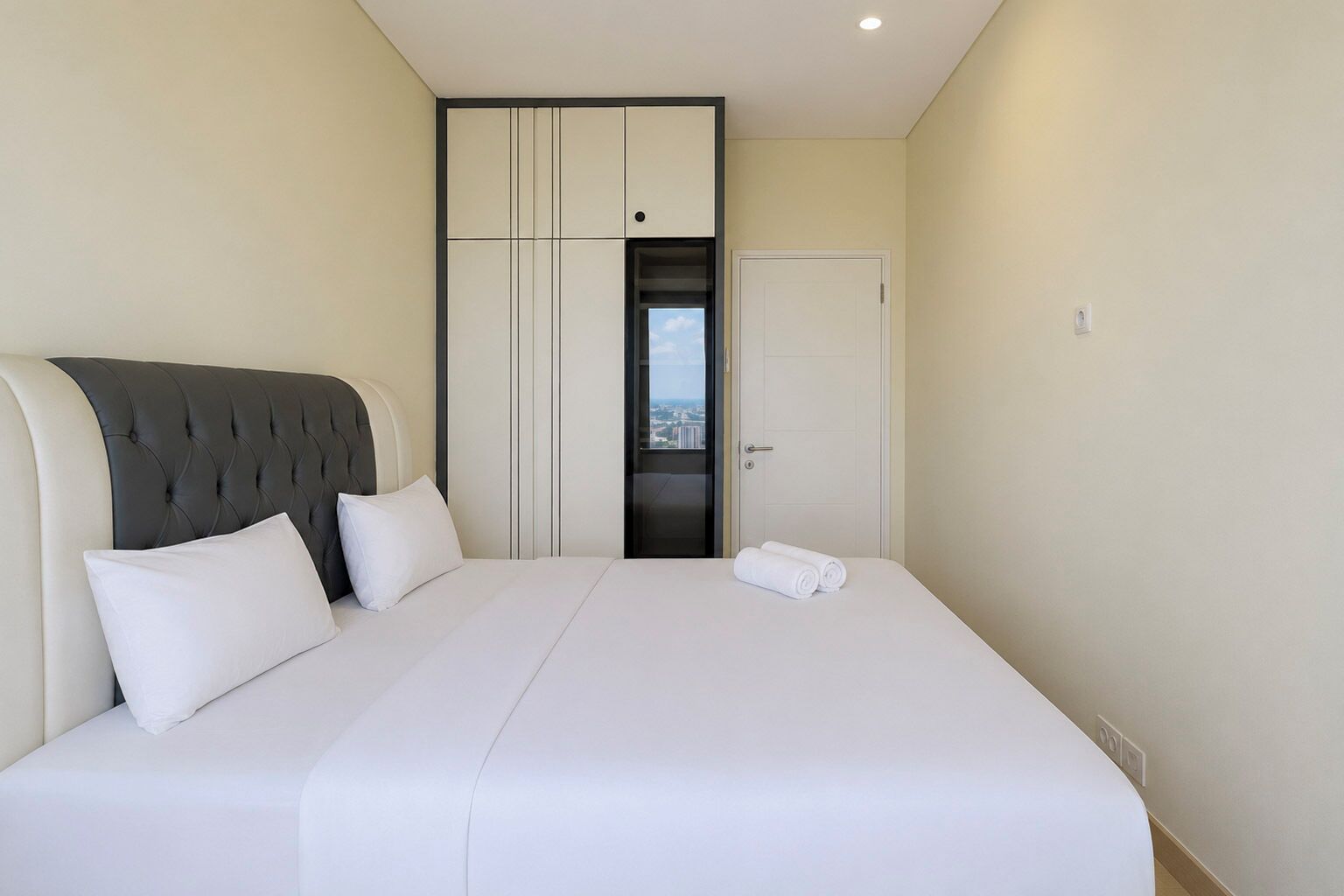 A hotel room with a large bed, a headboard, a wardrobe, and a door leading to a balcony.