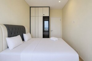 Ein Hotelzimmer mit einem großen Bett, einem Kopfteil, einem Kleiderschrank und einer Tür zu einem Balkon.