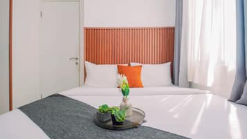 Et hotelværelse med en seng, et natbord med en plante og en dør.