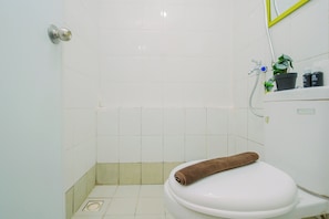 Et badeværelse med et hvidt toilet, et bruseområde og en vask med toiletartikler.