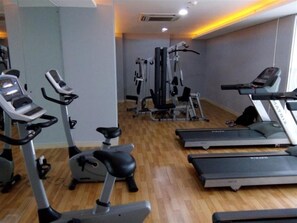 Un gimnasio con cintas de correr, elípticas y equipo de pesas.