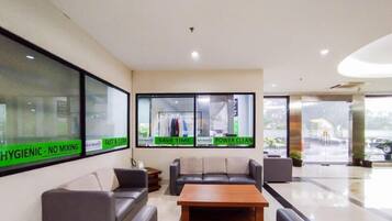 A hotel lobby with seating, a reception desk, and large windows with signage.