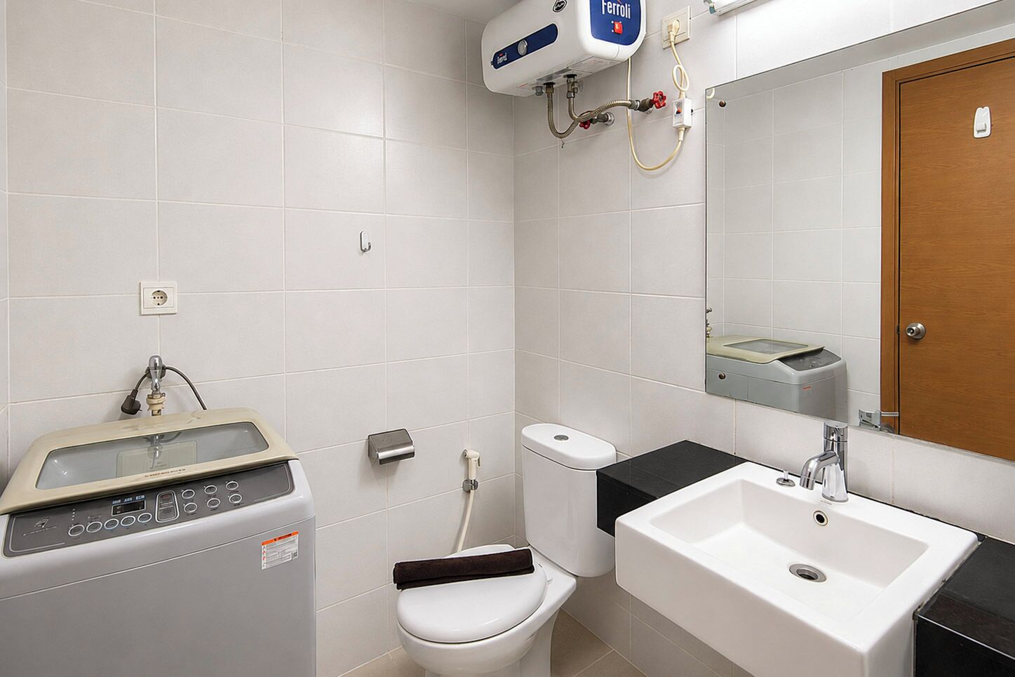 A bathroom with a toilet, bidet, sink, and a control panel.