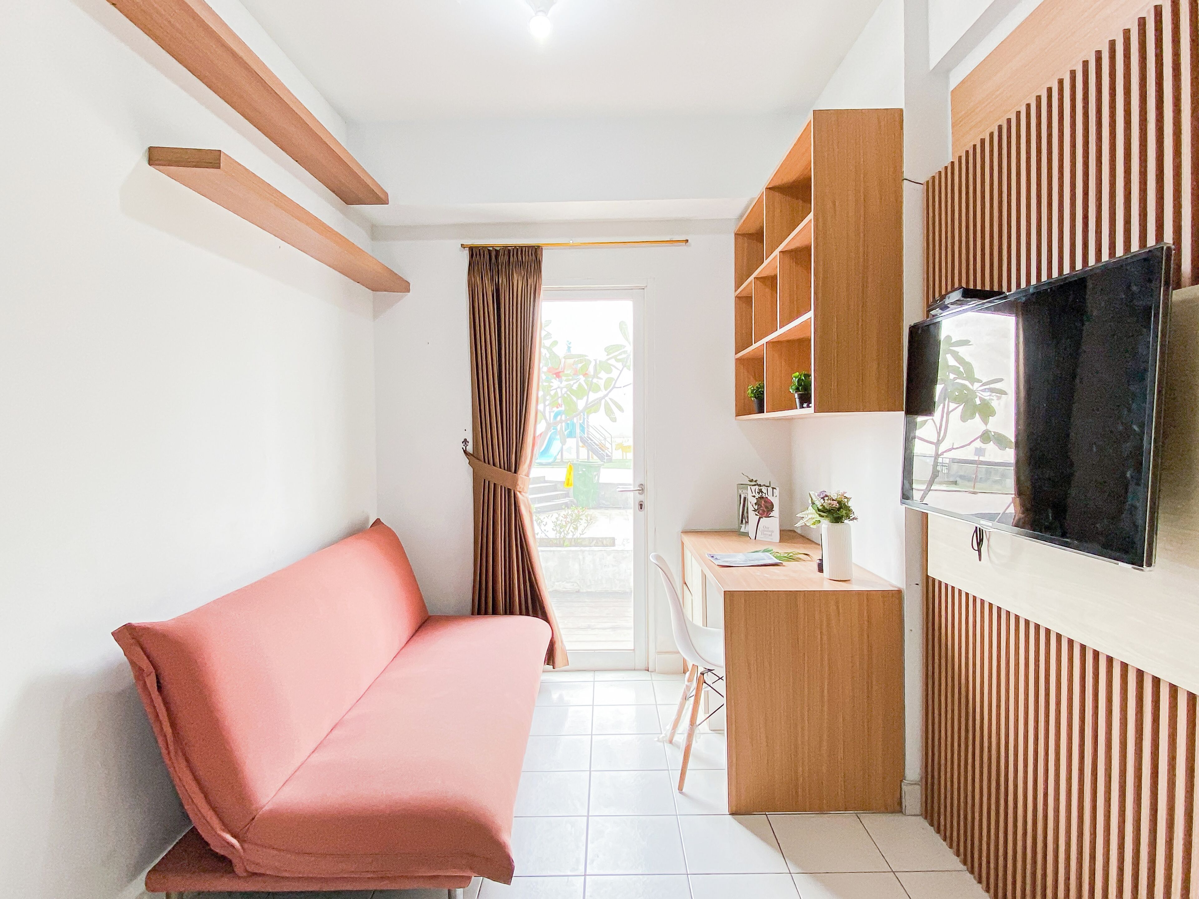 A modern living space with a sofa, a TV mounted on the wall, and a small desk area.