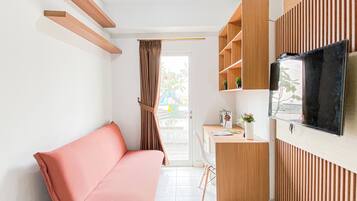 A modern living space with a sofa, a TV mounted on the wall, and a small desk area.