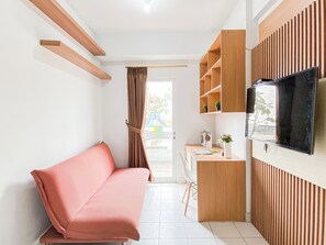 Un espacio de estar moderno con sofá, televisor montado en la pared y una pequeña zona de escritorio.