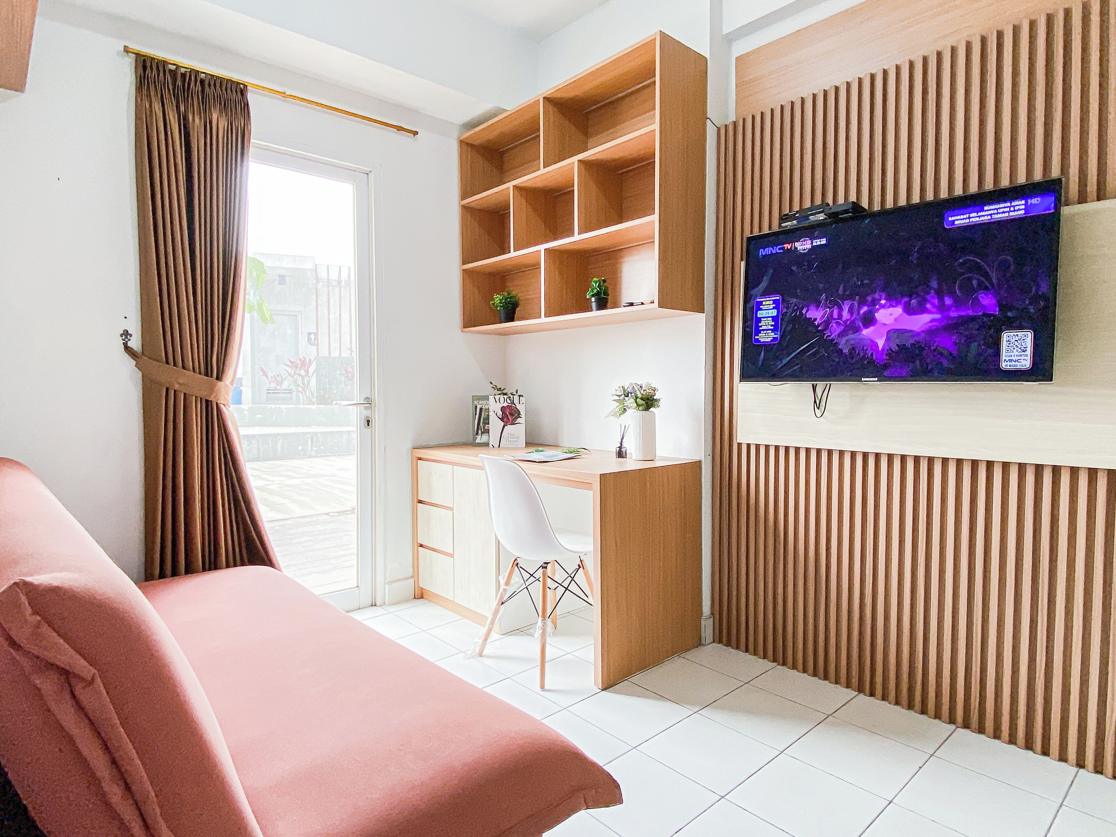 Una habitación moderna con cama, escritorio, televisor y ventana con cortinas.