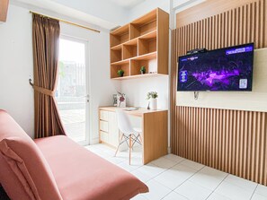 A modern room with a bed, a desk, a TV, and a window with curtains. - Cozy Compact 2Br At Apartment Patraland Urbano (Bekasi)