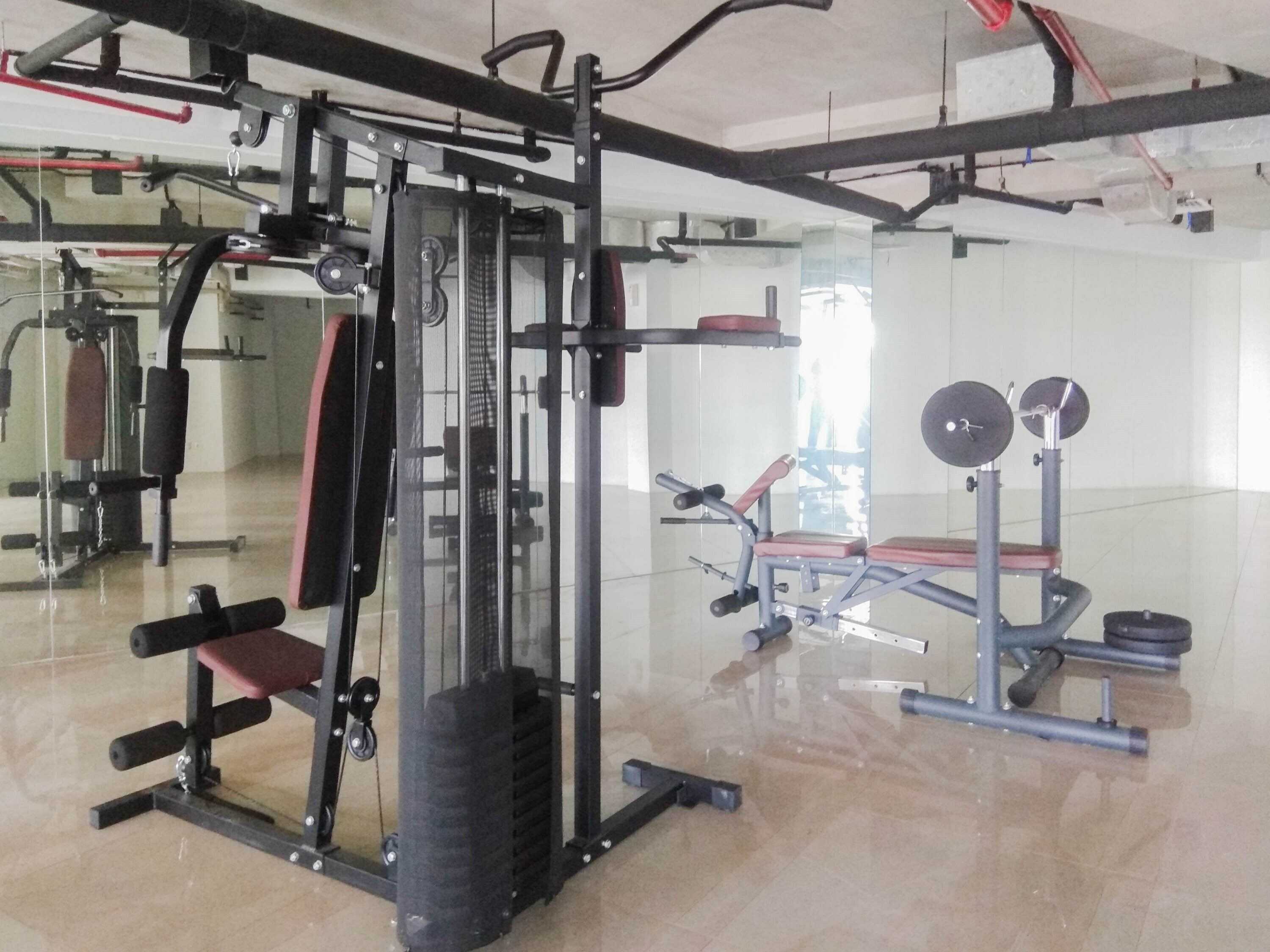 Un gimnasio con diferentes equipos de ejercicio, incluyendo una estructura para sentadillas, una prensa de banca y estaciones de levantamiento de pesas.