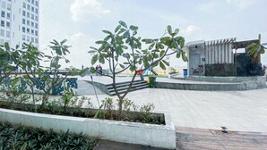 Una plaza pública con un parque infantil, zonas de estar y un edificio de diseño moderno.