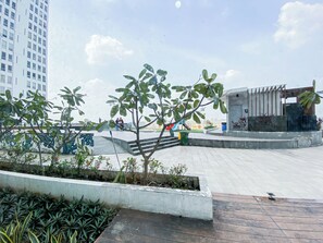 Uma praça pública com parquinho, áreas de estar e um edifício de design moderno.