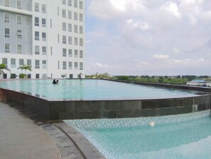 Uma piscina com borda azulejada, rodeada por um muro de pedra baixo.