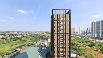 A modern high-rise building with a unique facade, surrounded by a green landscape and other high-rise buildings in the background.